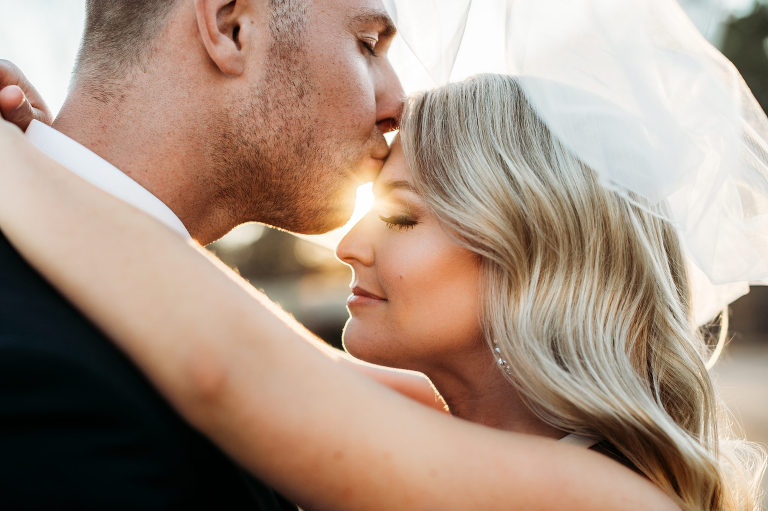 bride and groom kiss under wedding veil