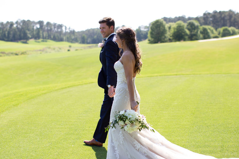 bride and groom walk together on a golf course