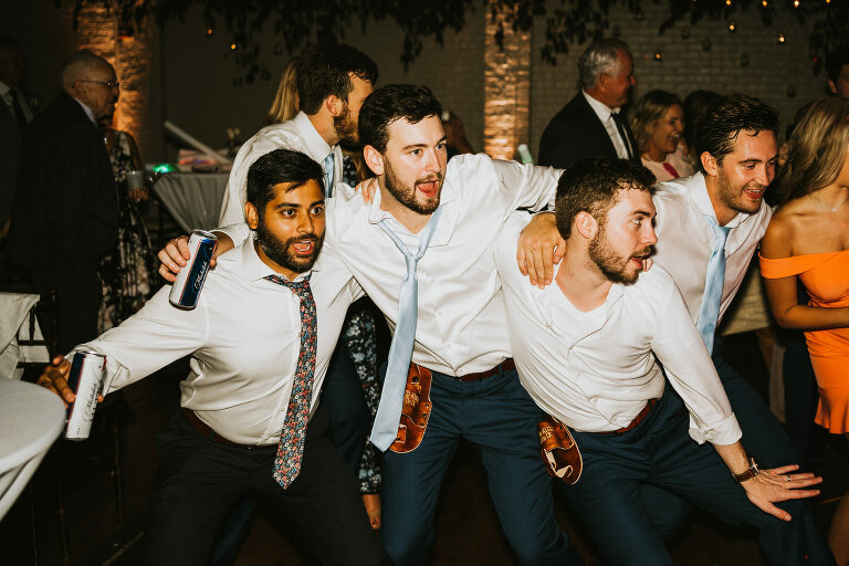 four guys dancing at a wedding reception