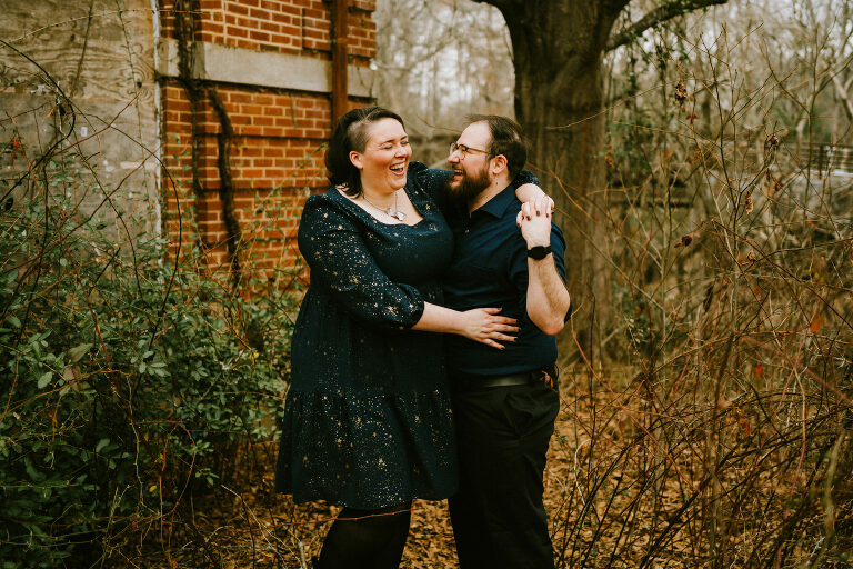 couple laughing in the woods while taking couples portraits