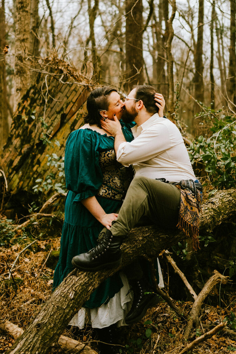couple kissing in the woods while wearing renfaire attire