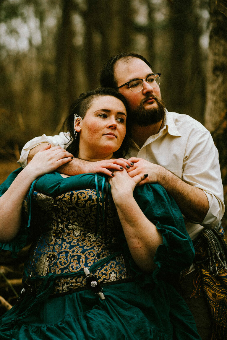 couple hugging in the woods while wearing renfaire attire